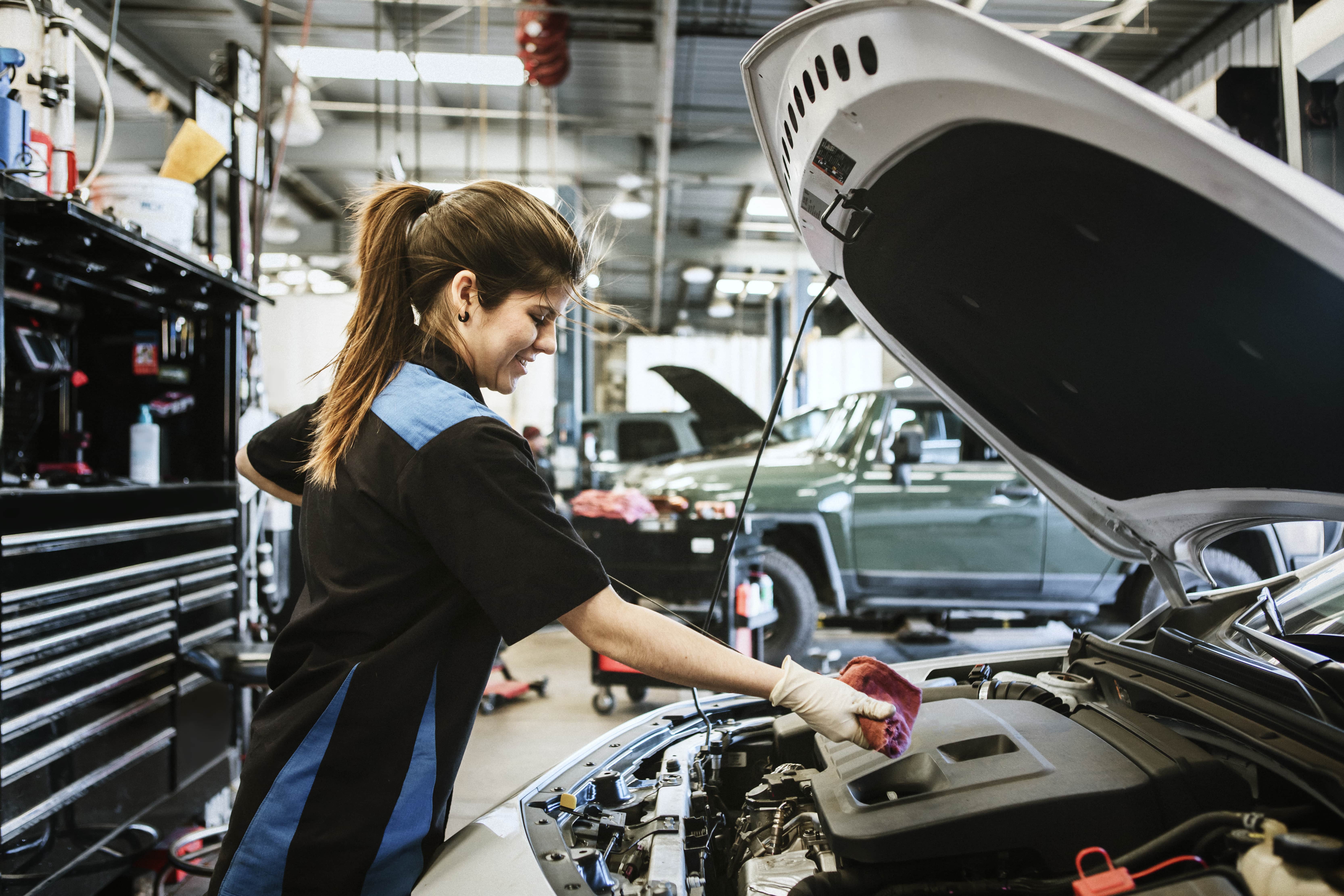women mechanic checks for oil in car